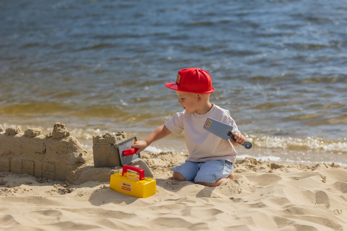 Bambino che costruisce un castello di sabbia in spiaggia, un tipico ricordo delle vacanze